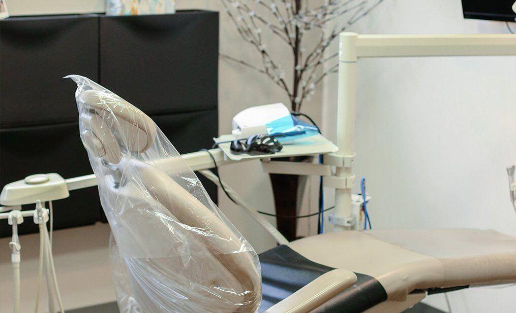 Dental treatment chair covered in clear plastic wrap